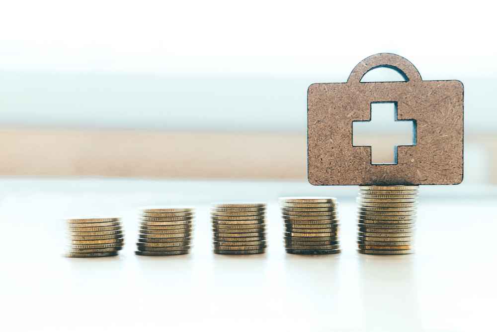 coin stacked in line and a bag with medical sign on top