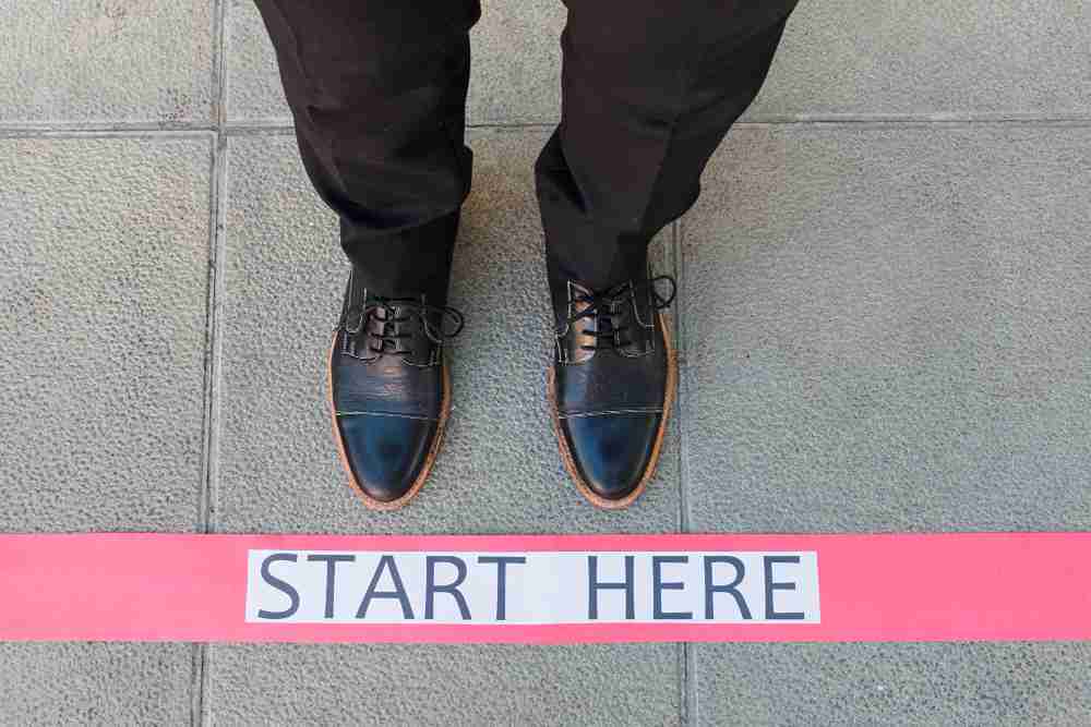 a person standing infront of start here sign